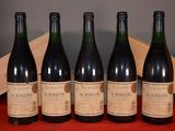 four bottles of wine are lined up on a red table