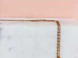 a close up of a gold necklace on a marble slab