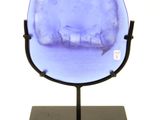 purple glass sculpture of a cat on a stand on a white background