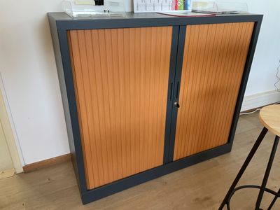 une armoire munie d'une porte, avec un tabouret devant