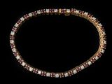 un gros plan d'un bracelet en or et rubis sur fond noir