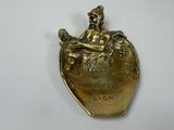 a gold plate with a figurine of a woman sitting on top of a heart