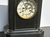 a black clock with a gold face sitting on a table