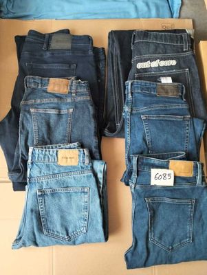 several pairs of men ' s jeans sitting on top of a cardboard box
