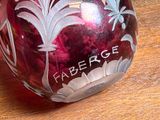 a red glass vase with white flowers on it on a wooden table