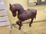 a wooden horse that is sitting on a glass table