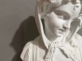 white marble bust of a woman with a hood on her head
