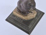 a statue of a rat sitting on top of a plaque