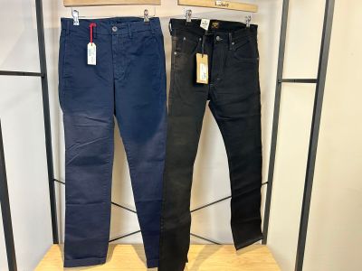 un jean noir et un jean bleu suspendus à un portant dans un magasin de vêtements
