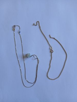 deux colliers en argent et une chaîne en argent sur fond blanc