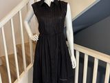 Le mannequin porte une robe noire et un chapeau de paille.