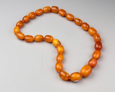 un collier de perles orange posé sur une surface blanche