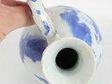 a hand that is holding a blue and white vase