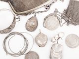 an assortment of silver jewelry including a purse, necklaces, and a coin