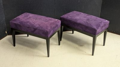 pair of purple upholstered stools in front of a black wall