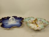 two porcelain dishes with swan designs on them sitting on a table