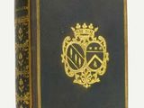 un vieux livre orné d'un emblème doré posé sur une surface blanche