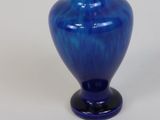 a blue glass vase sitting on a white surface