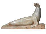 statue d'un phoque posée sur un socle en bois, sur fond blanc