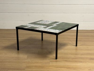 une petite table avec un plateau en carrelage posée sur un parquet