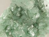 a large cluster of green crystals on a white surface