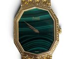 a close up of a gold watch with a green face