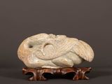 une photo d'une sculpture représentant un oiseau posée sur un socle en bois