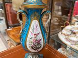 a blue and gold vase on a table in front of a glass case