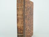 an old book sitting on top of a white table next to a white wall