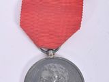 an old medal with a red ribbon on a white background