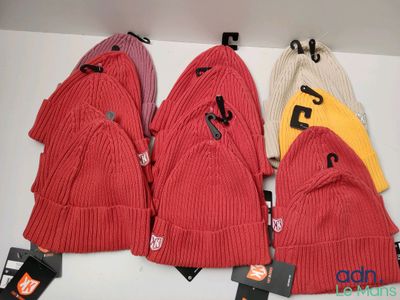 several hats are hanging on a wall with tags on them