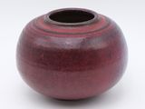 a red vase that is sitting on a white surface