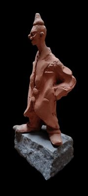 une sculpture en argile représentant un homme debout sur un rocher