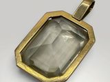 a close up of a gold pendant with a faceted grey stone