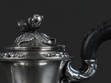 a silver tea pot with a handle on a table