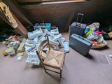 une pièce avec une chaise, une valise et d'autres objets posés par terre