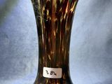 un vase marron et noir, muni d'une étiquette, posé sur un tissu bleu