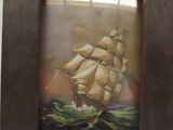 painting of a sailing ship in a wooden frame on a wall