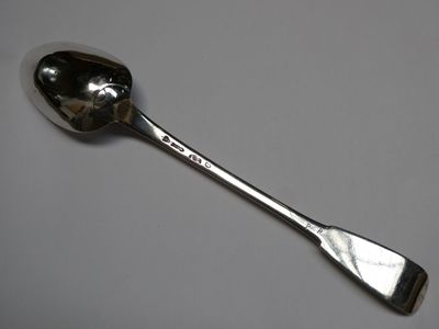 cuillère en argent posée sur une surface blanche, avec un manche en argent