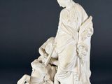 a white statue of a woman sitting on a chair with a dog