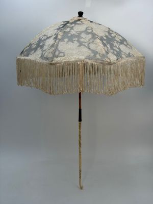 un parapluie blanc orné de franges, sur fond blanc