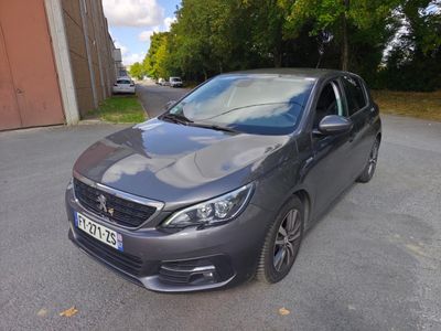 La voiture grise est garée sur le parking, à côté d'un immeuble.