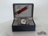 a watch in a box on a table next to some screws