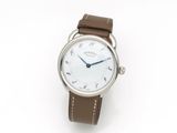 gros plan d'une montre sur une surface blanche avec un bracelet marron