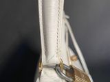 close up of a white purse with a gold lock on the handle