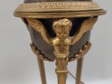 a gold and black vase on a stand on a white surface