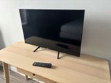 une télécommande posée sur une table devant un téléviseur