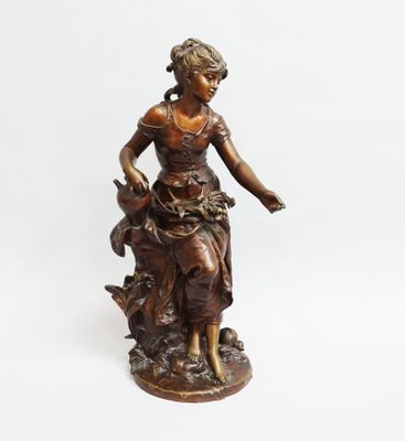 a bronze statue of a woman sitting on top of a rock