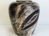 un vase noir et blanc posé sur une surface blanche