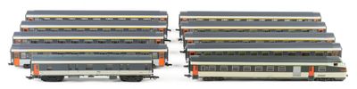 several model trains are lined up in rows on a white surface